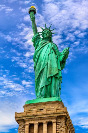 Téléchargez les photos : Statue de la Liberté contre le ciel bleu avec un beau fond nuageux à New York, NY, USA - en image libre de droit