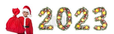 Téléchargez les photos : Garçon Père Noël tenant un sac de Noël et 2023 nombre fait par branches arbre de Noël isolé sur fond blanc - en image libre de droit