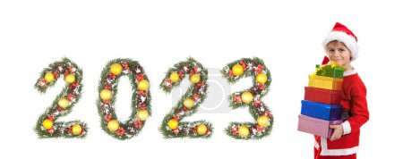 Téléchargez les photos : Garçon Père Noël tient un cadeau de Noël et 2023 nombre fait par branches d'arbre de Noël isolé sur fond blanc - en image libre de droit