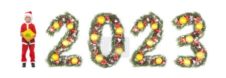 Téléchargez les photos : Garçon Père Noël tient un cadeau de Noël et 2023 nombre fait par branches d'arbre de Noël isolé sur fond blanc - en image libre de droit