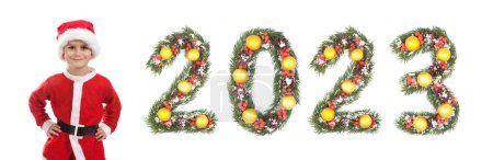 Photo for Boy dressed as Santa Claus and 2023 number made by christmas tree branches isolated on white background - Royalty Free Image