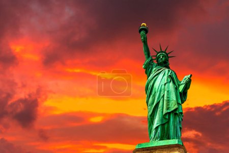 Téléchargez les photos : Statue de la Liberté contre le ciel couchant avec un beau fond nuageux à New York, NY, USA - en image libre de droit