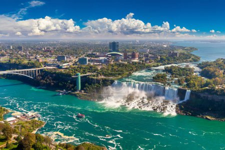Téléchargez les photos : Vue aérienne panoramique du côté canadien des chutes Niagara, des chutes American et du pont international Rainbow par une journée ensoleillée à Niagara Falls, Ontario, Canada - en image libre de droit