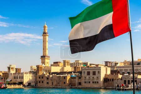 Foto de Focus on a flag of   United Arab Emirates flag against  bay Creek and Grand Bur Dubai Masjid Mosque in Dubai, United Arab Emirates - Imagen libre de derechos