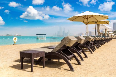 Foto de Tumbonas y sombrillas en la playa de hotel de lujo en Abu Dhabi en un día de verano, Emiratos Árabes Unidos - Imagen libre de derechos