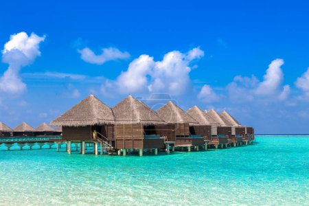 Foto de Water Villas (Bungalows) y puente de madera en la playa tropical de las Maldivas en el día de verano - Imagen libre de derechos