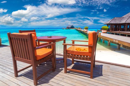 Téléchargez les photos : Table et chaises au restaurant de plage tropicale de luxe dans une journée d'été ensoleillée - en image libre de droit
