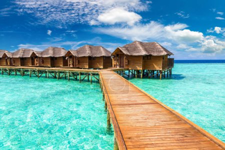 Foto de Water Villas (Bungalows) y puente de madera en la playa tropical de las Maldivas en el día de verano - Imagen libre de derechos