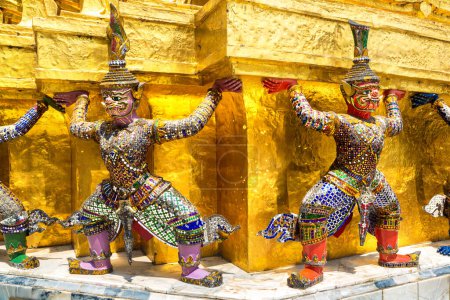 Foto de Estatuas del Guardián del Demonio están apoyando la estupa Chedi dorada en el templo de Wat Phra Kaew en un día soleado - Imagen libre de derechos