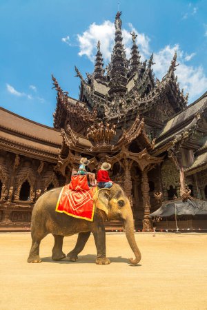 Photo for Tourists ride elephant around the Sanctuary of Truth in Pattaya, Thailand in a summer day - Royalty Free Image