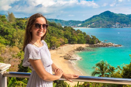 Woman traveler wearing blue dress at  Panoramic aerial view of Laem Sing beach on Phuket island, Thailand in a sunny day
