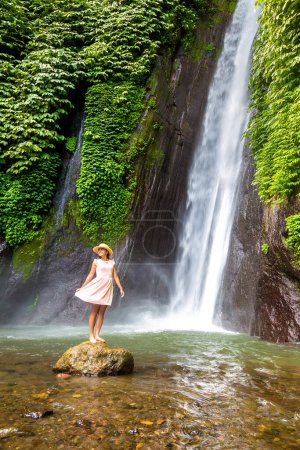Téléchargez les photos : Femme voyageuse à la cascade Munduk à Bali, Indonésie par une journée ensoleillée - en image libre de droit