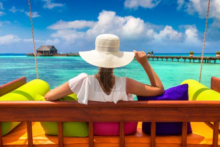 Foto de Hermosa mujer está sentada en columpio en la playa tropical de lujo en un día soleado de verano - Imagen libre de derechos