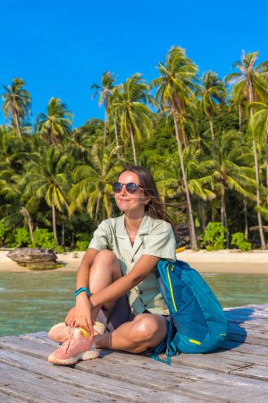 Téléchargez les photos : Femme voyageur assis à jetée en bois (pont) à la belle plage tropicale - en image libre de droit