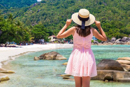 Woman traveler wearing pink dress and straw hat at  Silver Beach on Koh Samui island, Thailand in a summer day