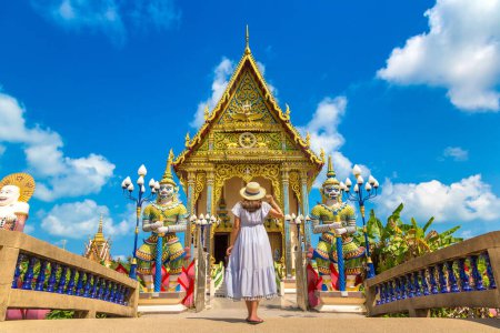 Photo for Woman traveler wearing blue dress and straw hat at Wat Plai Laem Temple, Samui, Thailand in a summer day - Royalty Free Image