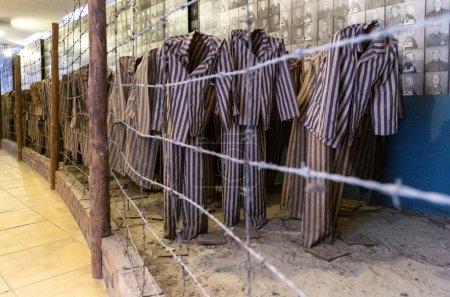 Téléchargez les photos : OSWIECIM, POLOGNE - 7 SEPTEMBRE 2022 : Exposition avec vêtements de prisonniers dans le camp de concentration d'Auschwitz par une journée ensoleillée, Oswiecim, Pologne - en image libre de droit