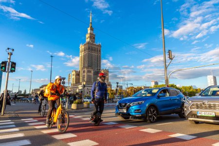 Photo for WARSAW, POLAND - SEPTEMBER 19, 2022: Cyclists cross the road and The Palace of Culture and Science - symbol of Warsaw, Poland - Royalty Free Image