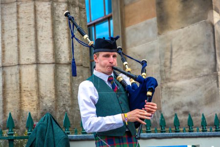 Téléchargez les photos : EDINBURGH, Royaume-Uni - 11 JUIN 2022 : Bagpiper jouant de la musique avec cornemuse près du château d'Édimbourg à Édimbourg, Écosse, Royaume-Uni - en image libre de droit