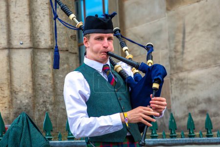 Foto de EDINBURGH, Reino Unido - 11 de junio de 2022: Bagpiper toca música con gaita cerca del Castillo de Edimburgo en Edimburgo, Escocia, Reino Unido - Imagen libre de derechos