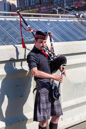 Foto de EDINBURGH, Reino Unido - 11 de junio de 2022: Bagpiper toca música con gaita cerca del Castillo de Edimburgo en Edimburgo, Escocia, Reino Unido - Imagen libre de derechos