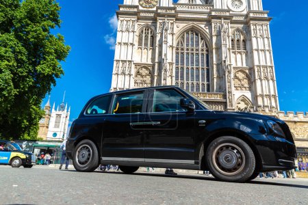 Téléchargez les photos : LONDRES, Royaume-Uni - 17 JUIN 2022 : Un jour d'été ensoleillé à Londres (Royaume-Uni), taxi londonien (cabine noire) et abbaye de Westminster - en image libre de droit