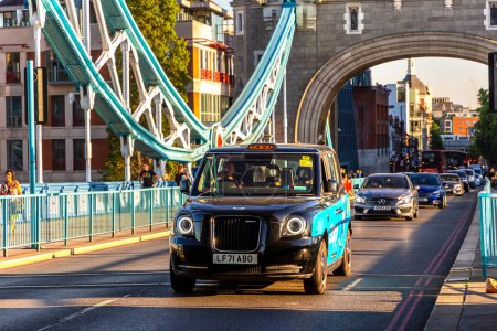 Téléchargez les photos : LONDRES, Royaume-Uni - 17 JUIN 2022 : Taxi à Londres (cabine noire) sur le pont historique Tower Bridge à Londres au coucher du soleil, Royaume-Uni - en image libre de droit