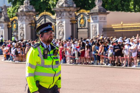 Téléchargez les photos : LONDRES, ROYAUME-UNI - 17 JUIN 2022 : Un officier de police métropolitain patrouille lors du changement de garde devant Buckingham Palace à Londres par une journée ensoleillée d'été, Royaume-Uni - en image libre de droit