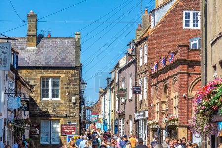 Téléchargez les photos : WHITBY, Royaume-Uni - 13 AOÛT 2022 : Rue touristique typique de Whitby - Station touristique populaire par une journée ensoleillée d'été, North Yorkshire, Royaume-Uni - en image libre de droit