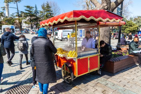 Foto de ISTANBUL, TURQUÍA - 10 DE ABRIL DE 2022: Vendedor turco callejero vende maíz a la parrilla tradicional turco caliente en Estambul, Turquía en un día soleado - Imagen libre de derechos