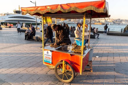Foto de ISTANBUL, TURQUÍA - 10 DE ABRIL DE 2022: Vendedor turco callejero vende castaño asado tradicional turco en Estambul, Turquía en un día soleado - Imagen libre de derechos