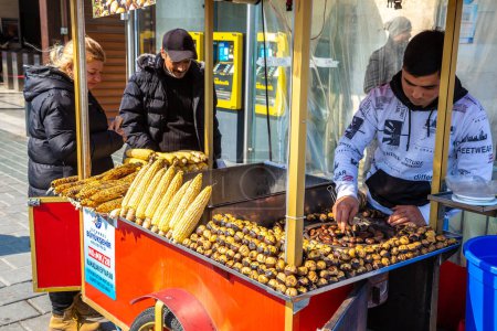 Téléchargez les photos : ISTANBUL, TURQUIE - 10 AVRIL 2022 : Un vendeur turc de rue vend du maïs grillé et du châtaignier turcs traditionnels à Istanbul, en Turquie, par une journée ensoleillée - en image libre de droit