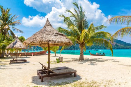 Téléchargez les photos : Parasol, transat et palmier sur une plage tropicale par une journée ensoleillée - en image libre de droit