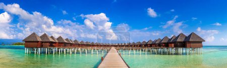 Foto de Panorama de villas acuáticas (bungalows) y embarcadero de madera en la playa tropical en las Maldivas en el día de verano - Imagen libre de derechos