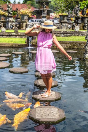 Photo for Woman traveler wearing white dress and straw hat at  Taman Tirtagangga temple on Bali, Indonesia in a sunny day - Royalty Free Image