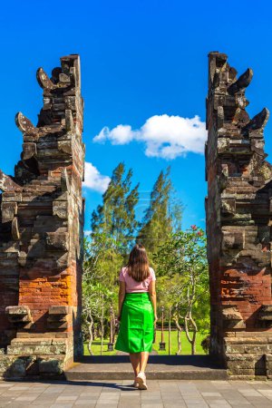 Foto de Mujer viajera en la puerta de entrada tradicional al templo Taman Ayun en Bali, Indonesia en un día soleado - Imagen libre de derechos