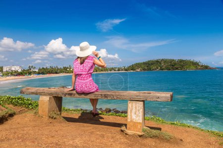 Photo for Woman seatted on a bench at Mirissa tropical Beach in a sunny day in Sri Lanka - Royalty Free Image