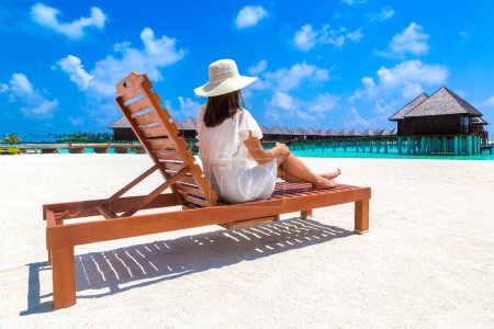 Photo for Beautiful woman relaxing in sunbed at luxury tropical beach in a sunny summer day - Royalty Free Image