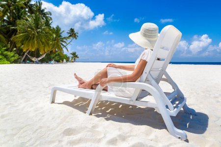 Foto de Hermosa mujer relajándose en el solárium en la playa tropical de lujo en un día soleado de verano - Imagen libre de derechos