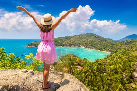 Photo for Woman traveler wearing pink dress and straw hat at viewpoint with Panoramic aerial view of Koh Tao island, Thailand - Royalty Free Image