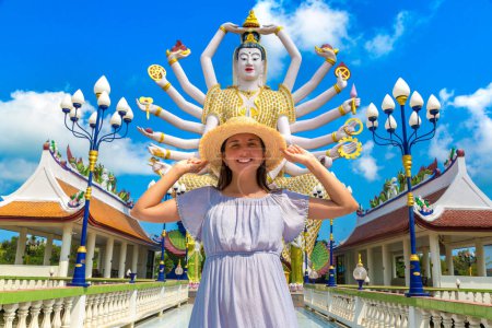 Photo for Woman traveler wearing blue dress and straw hat at  Statue of Shiva in Wat Plai Laem Temple, Samui, Thailand in a summer day - Royalty Free Image