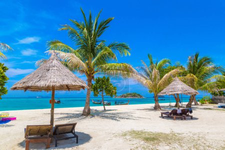 Téléchargez les photos : Parasol, transat et palmier sur une plage tropicale par une journée ensoleillée - en image libre de droit