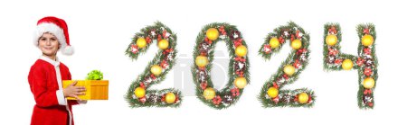 Téléchargez les photos : Garçon Père Noël tient un cadeau de Noël et 2024 nombre fait par branches d'arbre de Noël isolé sur fond blanc - en image libre de droit