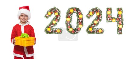 Photo for Boy Santa Claus is holding a christmas gift and 2024 number made by christmas tree branches isolated on white background - Royalty Free Image