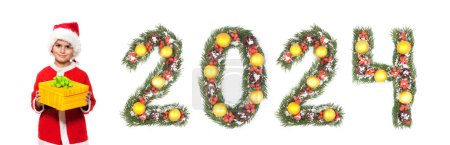 Téléchargez les photos : Garçon Père Noël tient un cadeau de Noël et 2024 nombre fait par branches d'arbre de Noël isolé sur fond blanc - en image libre de droit