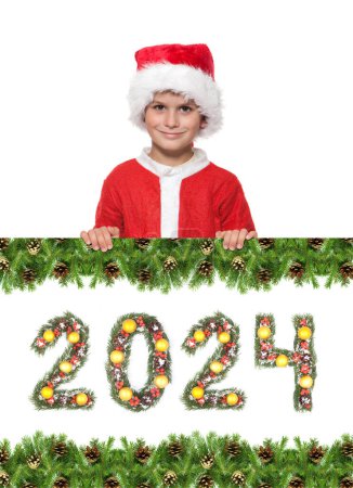 Photo for Boy Santa Claus is holding a christmas poster and 2024 number made by christmas tree branches isolated on white background - Royalty Free Image
