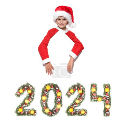 Photo for Boy Santa Claus is holding a christmas poster and 2024 number made by christmas tree branches isolated on white background - Royalty Free Image