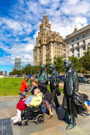 Photo for LIVERPOOL, UK - AUGUST 16, 2023: Tourists take pictures in front of The Beatles Statue in Liverpool stands at the Pier Head on the side of river Mersey in a sunny day, United Kingdom - Royalty Free Image