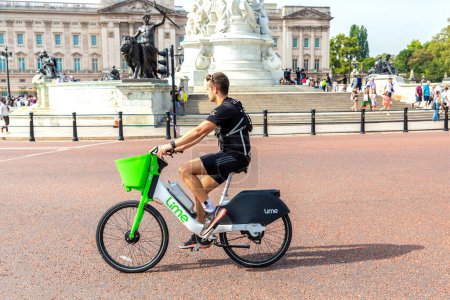Téléchargez les photos : LONDRES, Royaume-Uni - 8 SEPTEMBRE 2023 : Man ride Lime rental e-bike in front of Buckingham Palace in London in a sunny day, Angleterre, Royaume-Uni - en image libre de droit