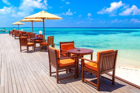Photo for Table and chairs at luxury tropical beach restaurant in a sunny summer day - Royalty Free Image